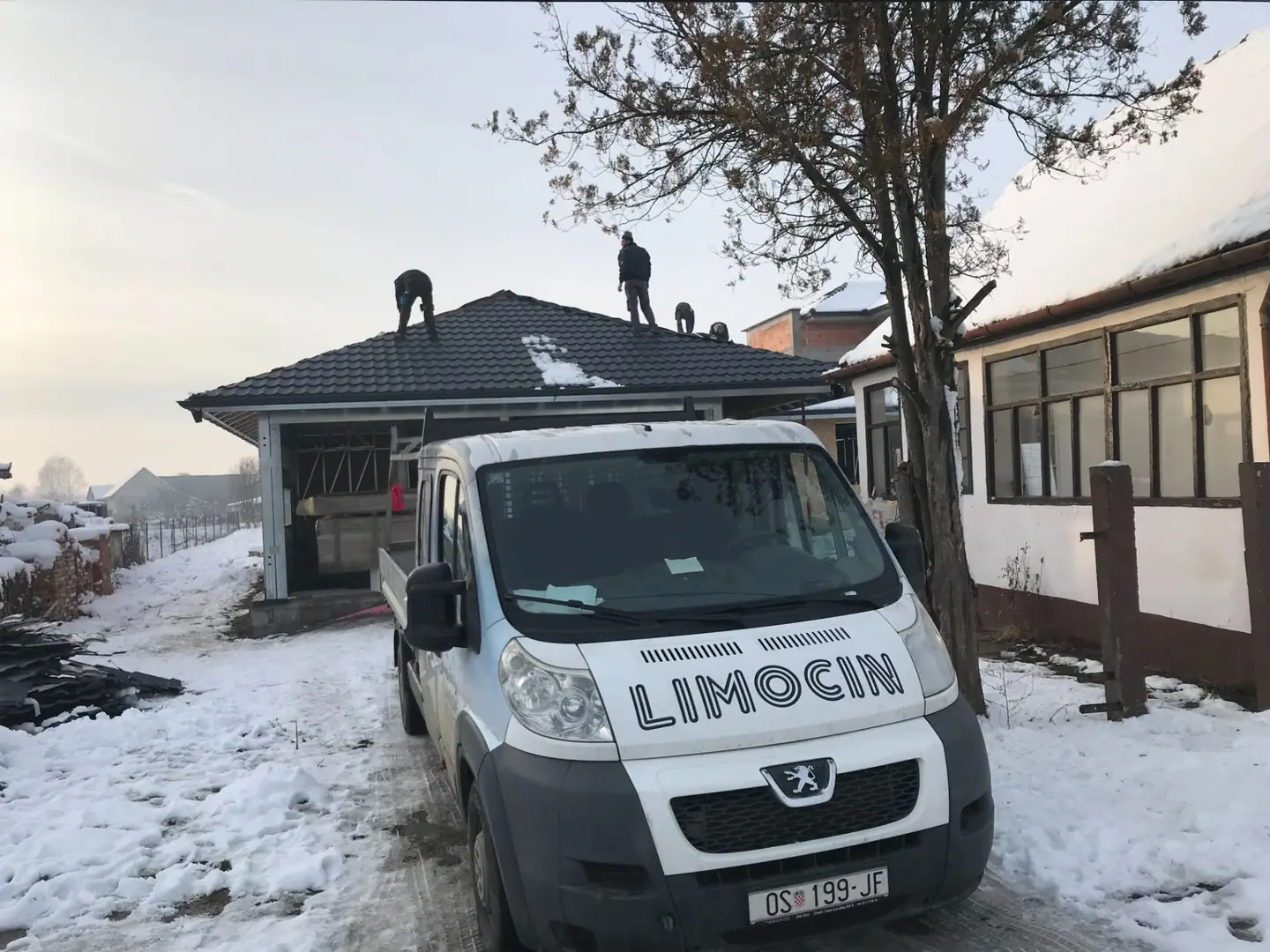 Montaža krova zimi: ekipa na krovu i vozilo Limocin